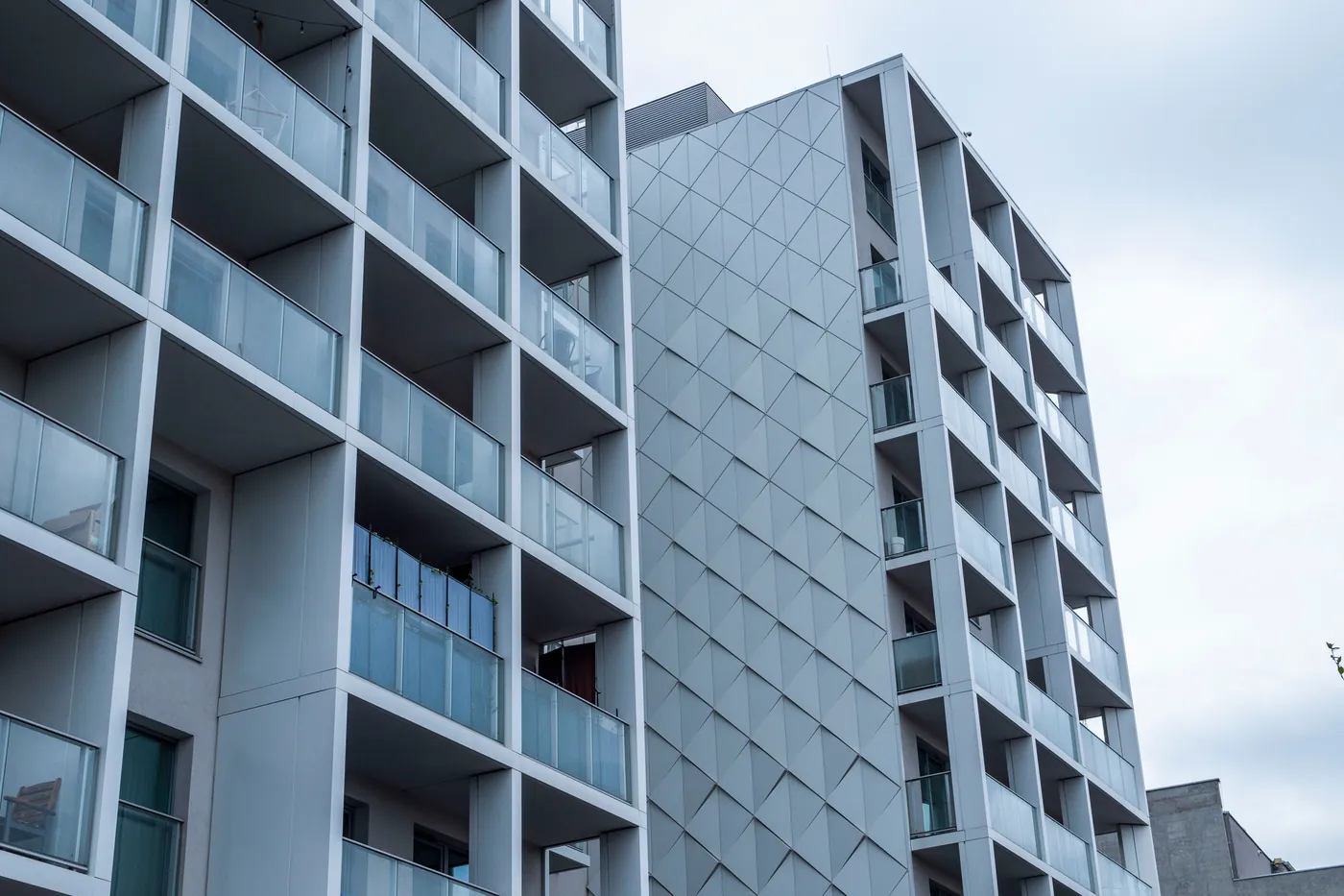 The glass facade of a contemporary apartment building under a cloudy sky