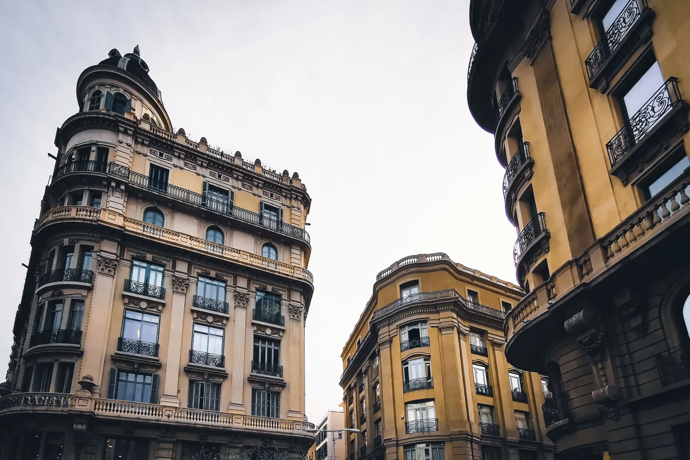 Low-angle view of classical stone facades against a pale sky