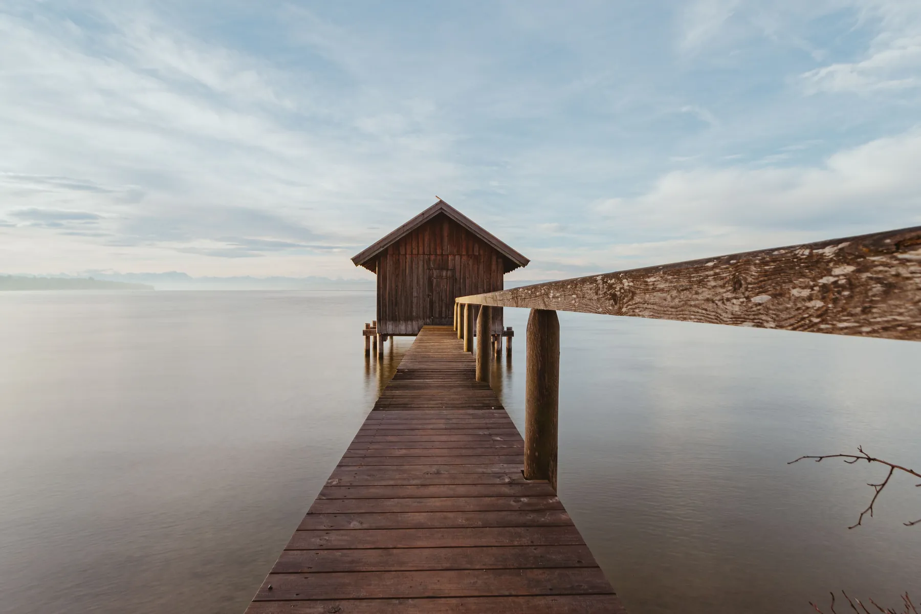 A wooden pier and boathouse on a still lake at daybreak