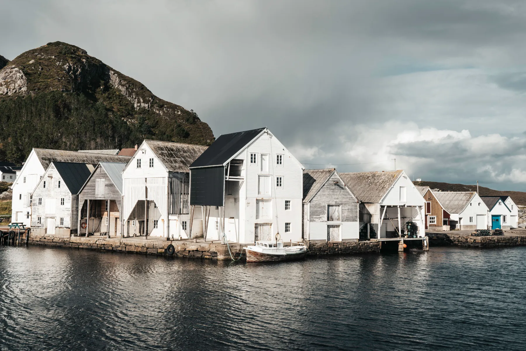 A harbour village of white timber houses below a mountainous shore