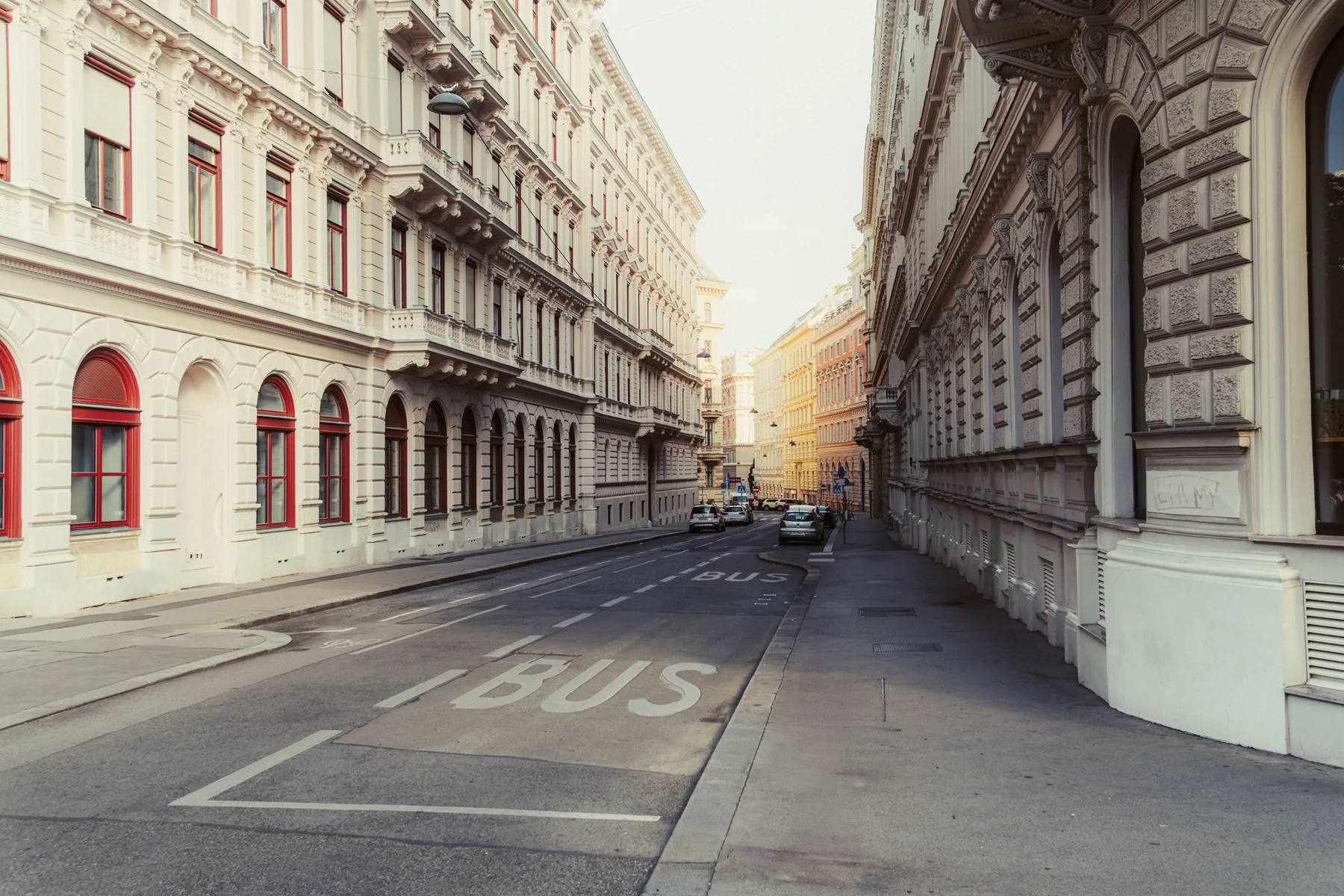 A quiet street of classical stone apartment buildings in soft light